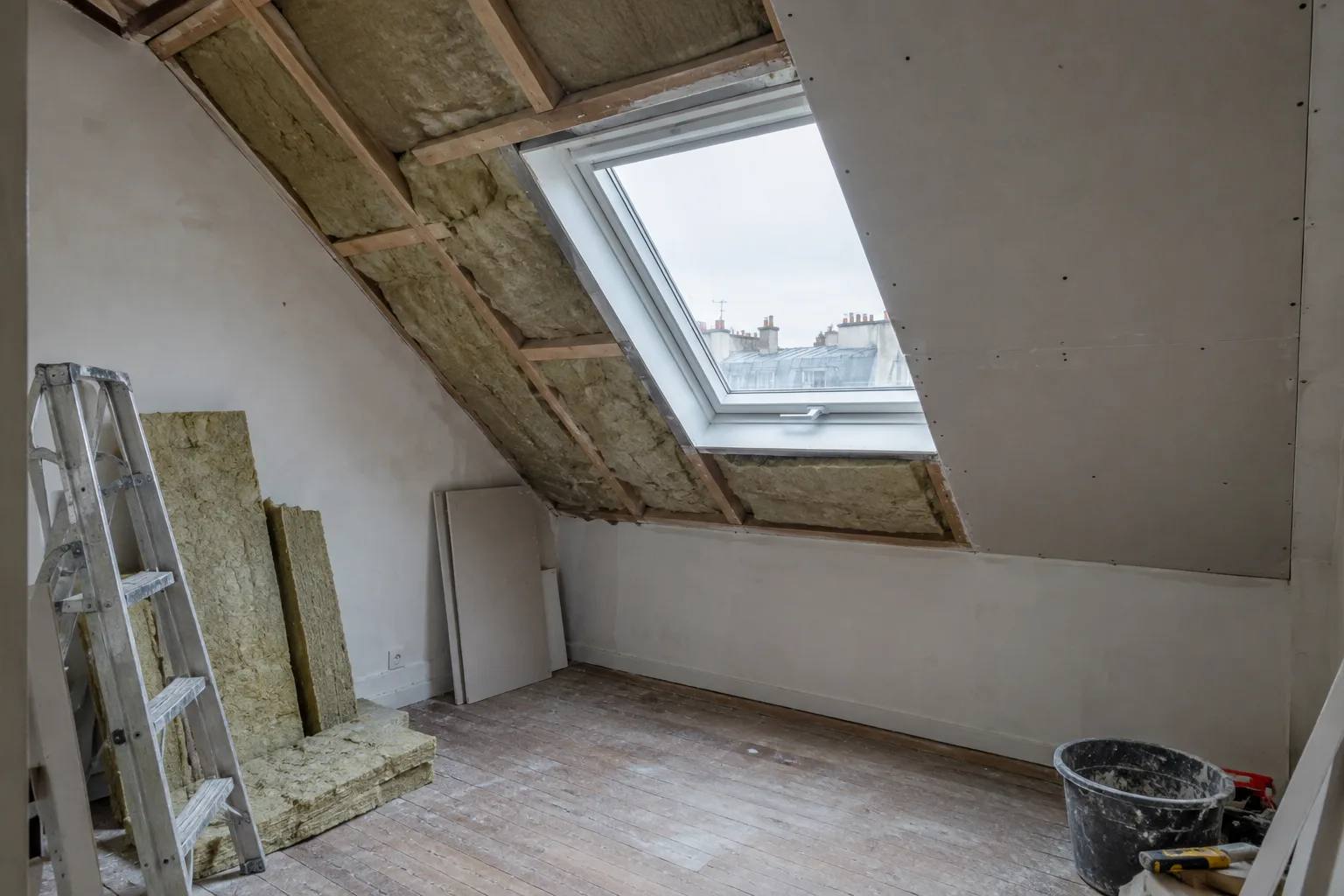 Isolation d'un logement sous les toits, laine minérale entre les chevrons et plaques de plâtre posées sur la moitié du rampant